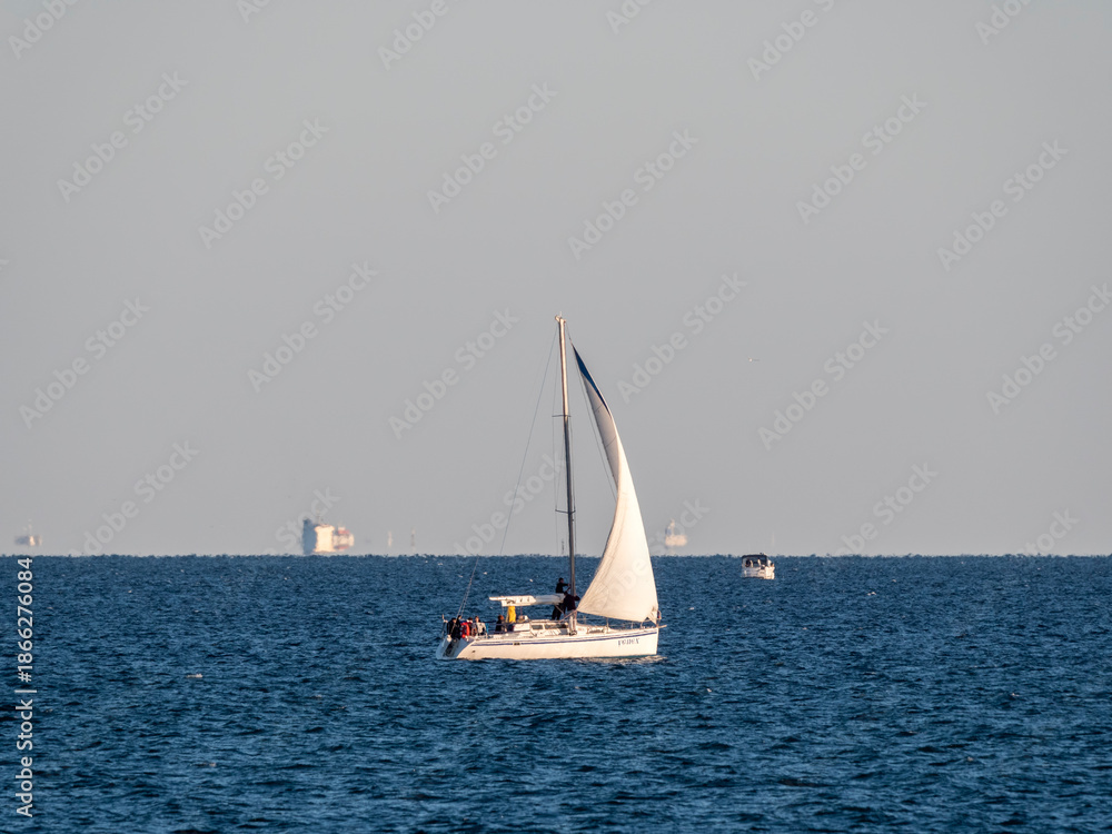 Obraz premium August 22 2025 Sailing yacht Uspekh with white sail on the Black Sea near Novorossiysk Russia. Recreational yacht moving along the coastline.