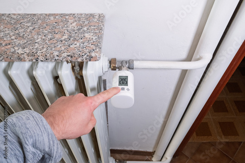 Tablou pe pânză Close-up of hand lowering smart radiator thermostat
