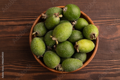 Ripe Feijoa in wooden bowl on brown wooden, top view, flat lay, close up