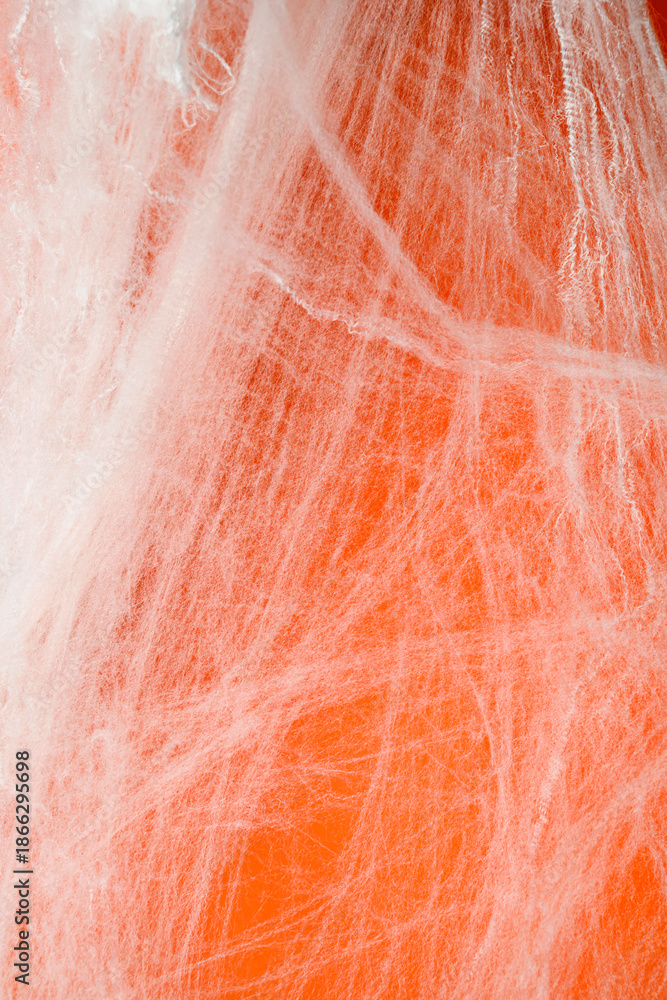 Fototapeta premium Spooky Halloween decoration with white cobweb on an orange background. Mockup, copy space, or template. Perfect for creating a festive atmosphere for Halloween parties or spooky projects