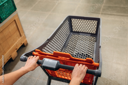 Wallpaper Mural Hands gripping shopping cart handle in a grocery store aisle, showcasing the shopping experience with vibrant colors and organized surroundings Torontodigital.ca