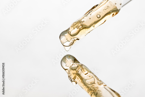 Two pipettes with yellow serum, aromatherapy gel on a light background.