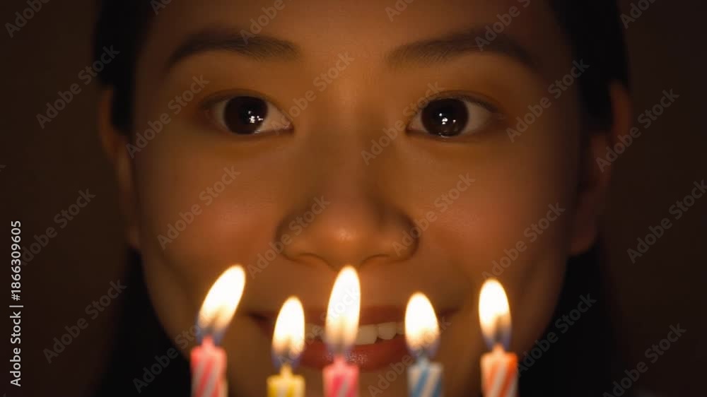custom made wallpaper toronto digitalYoung Asian girl celebrating her birthday with five lit candles in front of her face, creating a warm glow in a dark room.