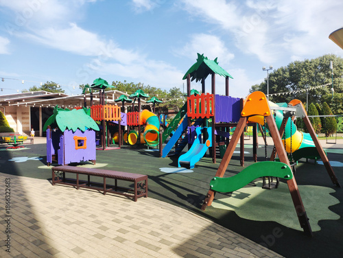 Wallpaper Mural Colorful outdoor children playground equipment; slides, tunnels, swings, climbing structures, playhouses; rubberized safety flooring; bright sunny day; blue sky; inviting recreation area Torontodigital.ca