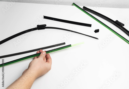 Hand of person replacing rubber blade element of car windshield wiper on white background, maintenance process for vehicle component