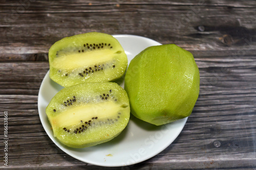 Peeled Kiwifruit kiwi, an edible berry from woody vines, known for its fuzzy brown skin, bright green or golden flesh, tiny black seeds, and sweet-tart flavor