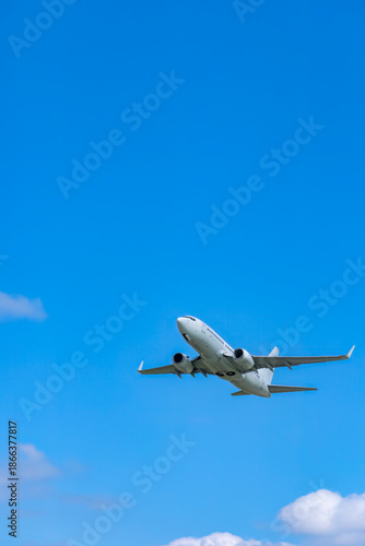 White passenger airplane taking off against blue sky