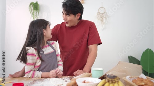 A family helping their daughter roll dough together in the kitchen, enjoying a fun baking moment