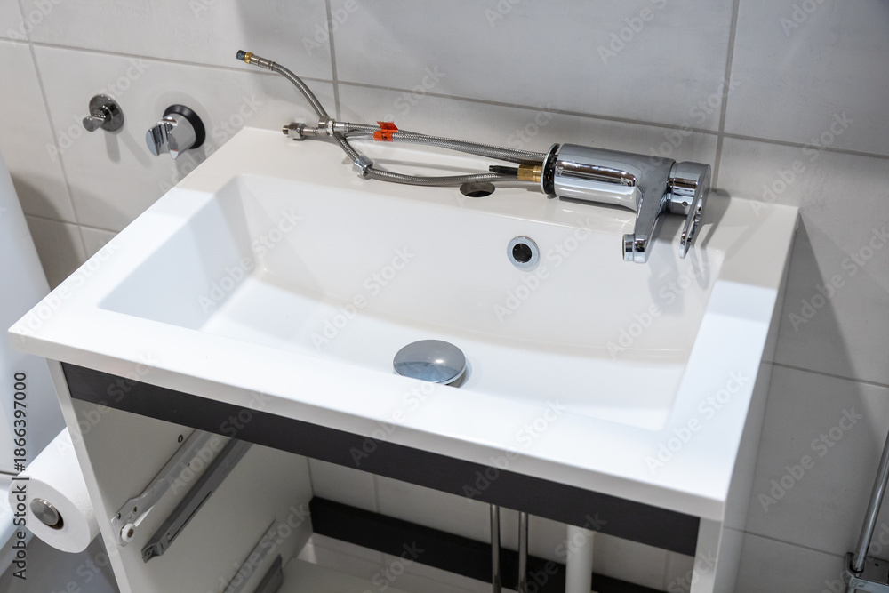 Fototapeta premium Bathroom sink during faucet replacement with tools around. Home renovation scene showing plumbing repair, maintenance, and installation work in progress