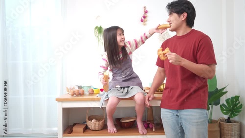 A father and daughter playfully sword-fight with baguettes in the kitchen, creating a fun and lively family cooking moment