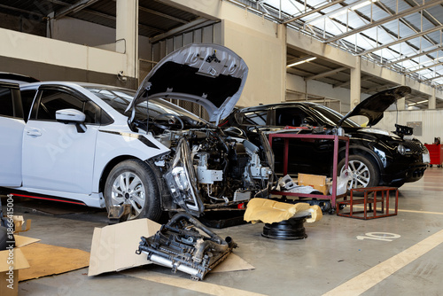 White car with dismantled front bumper during major repair in garage
