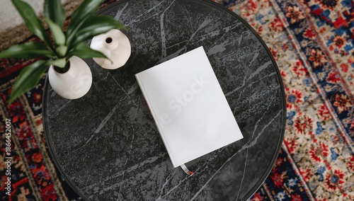 White Book on a Wooden Table Beside a Candle and Flowers in a Cozy Room Setting