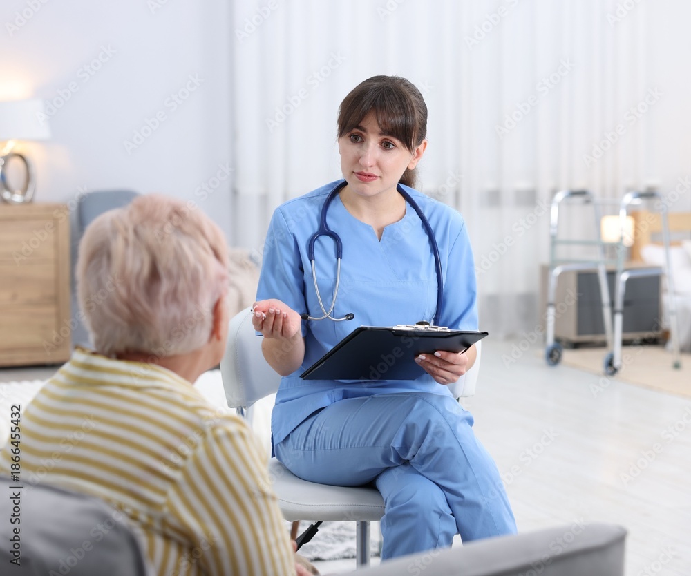 Fototapeta premium Care worker asking senior woman about her wellbeing at retirement home