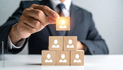 Businessperson placing glowing leader block atop employee pyramid