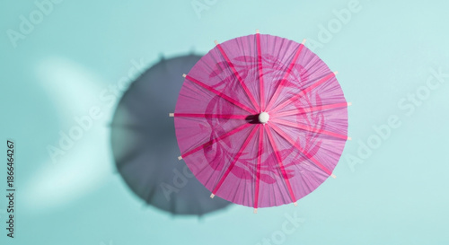 Delicate Pink Cocktail Umbrella Overhead on Light Blue Backdrop Summer Drink Accessory Tropical Decoration Paper Parasol Detail Shadow