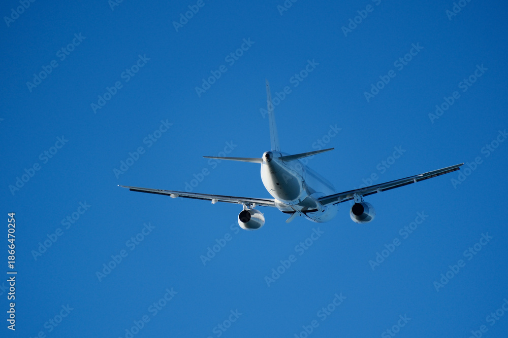 Fototapeta premium Commercial Airplane Departing After Takeoff, Rear View in Blue Sky. Passenger Airliner Flying Away on Departure, Back View
