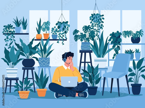 Man sitting on floor surrounded by plants working on laptop at home with chair beside him