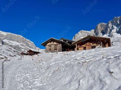 Charming wooden huts surrounded by snow in Partnun, with Sulzfluh and Scheienfluh in the background. Partner, Graubuenden, Switzerland.