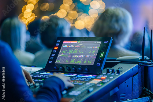 Valmiera, Latvia - December 29, 2025: Sound engineer adjusting audio mixer during live concert performance with blurred audience in background