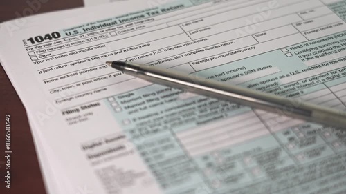 A taxpayer completes the 1040 Individual Income Tax Return form on a table. The form contains sections detailing personal information and income for the tax year 2025