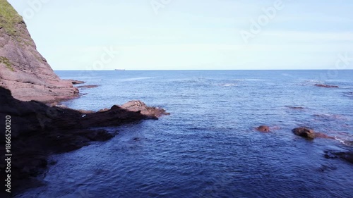 Through a natural arch in Aberdour beach area in Scotland.