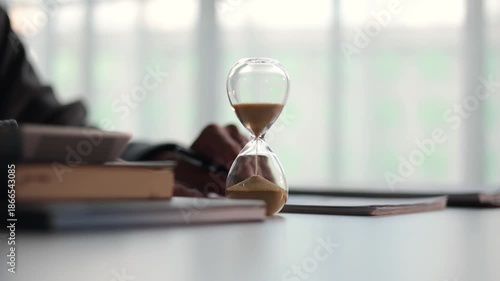 Selective focus on Sand Clocks. Businessman working at office desk. Time management concept.