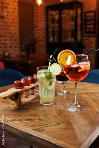 Enjoying a variety of refreshing drinks on a wooden table in a cozy restaurant setting with a lively atmosphere during the evening