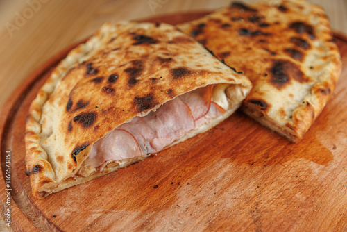 Explore delicious calzone with ham and cheese on wooden board served in a cozy kitchen area during dinner time