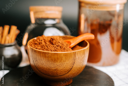Fotografija Bowl of cocoa powder with containers and cinnamon sticks arranged on a table