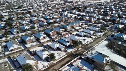 Frisco, Texas, USA - January 3rd, 2024: Drone view of extensive suburban neighborhood with hundreds of single-family homes, snow on roofs, streets and yards under sunny winter conditions
