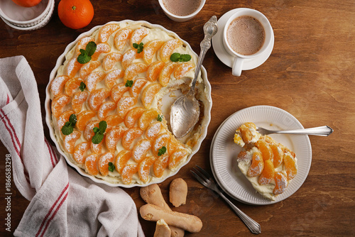 Bowl of mandarin tiramisu on the wooden table with hot chocolate, top view