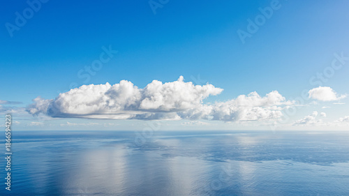 Cloudy seascape. Beautiful abstract nature background in blue tones showing large white clouds over blue ocean water, with a clear blue sky in the background
