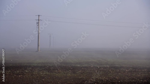 Morning fog over plowed field with electric pole at sunrise, 4K