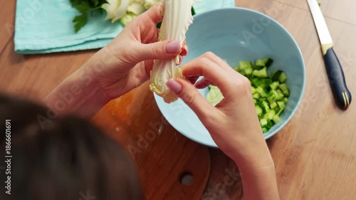Preparing fresh ingredients for a vibrant salad with chopped cucumbers and crisp lettuce in a cozy kitchen