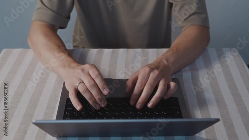 Close up top view of male hands typing on a laptop keyboard. Natural hand placement, smooth finger motion and calm everyday computer activity at home. High quality 4k footage