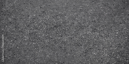 Rough dark gray asphalt road texture with a closeup pattern of stone material on a weathered black tarmac street pavement surface