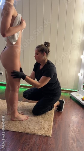 Full body massage session with therapist in black applying product on client’s legs while she stands