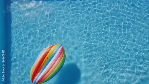 Tranquil Water Paradise: A vibrant, colorful inflatable float gently drifts across the shimmering surface of a crystal-clear, sunlit pool, inviting relaxation and carefree leisure.
