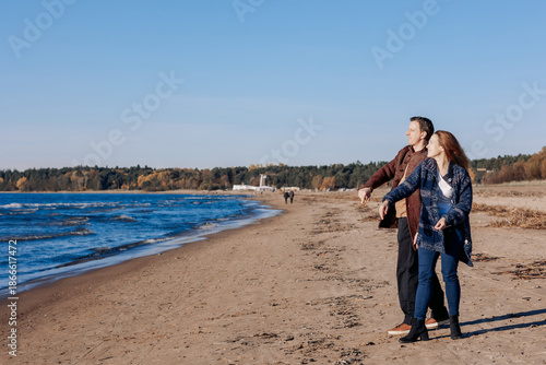Young carefree couple in love throwing pebbles, shells, stones into sea outdoors. Fun family game together. High quality photo