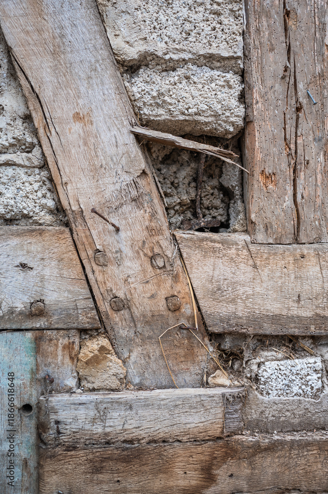 Obraz premium Alter Hauswand mit Brettern, Steinen und Beton. Historisches Bauwerk mit erkennbaren Altersspuren.