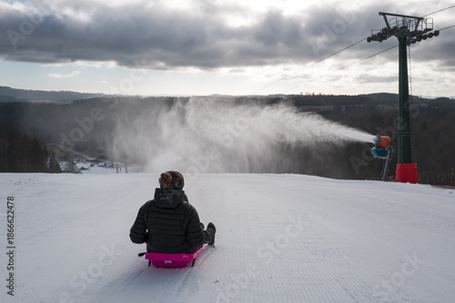 Foto Children on a bobsleigh ride downhill past a snow maker