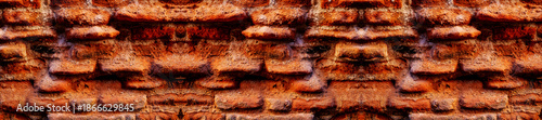 A close-up of a beat-up red brick wall with rough, uneven bricks in shades of red, orange, and brown, showing off years of wear and tear.