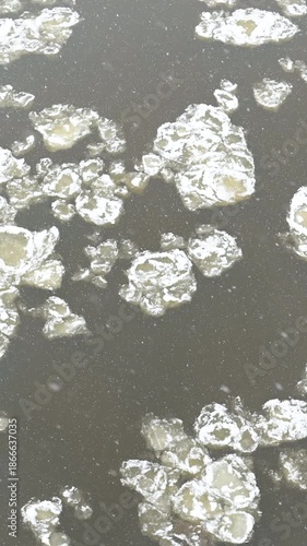 Top-down vertical view of river covered with pancake ice. Chilly moody winter day. Scenic winter landscape.