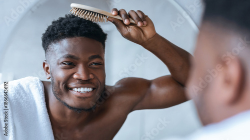 Bilde på lerret A man is brushing his hair in front of a mirror