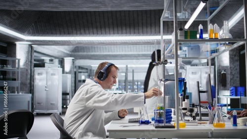 Konstfotografi Atypical researcher uses headset for focus music during experiment, distinct approach in laboratory science