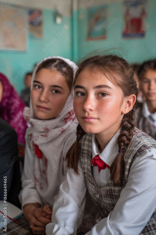 Fototapeta premium A close-up of Tajik students in school uniforms attentively learning in a simple classroom, reflecting hope for the future.