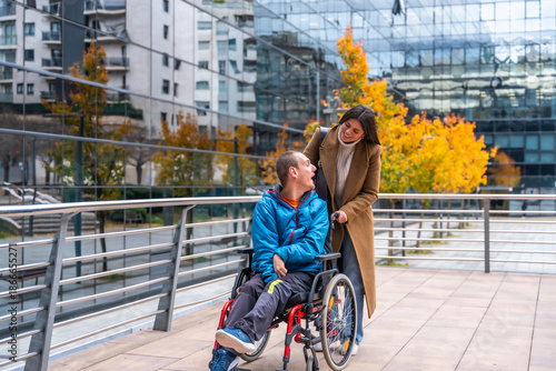 Caregiver pushing adult man in wheelchair in city