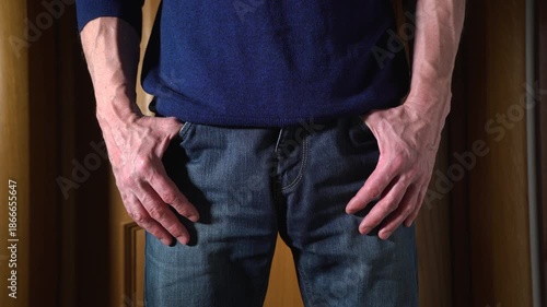 Annoyed adult man is nervously gesturing with his fingers. A close-up of a palms of an impatient man standing in a room with his hands in his jeans pockets. 4K