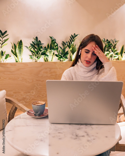 Woman suffering headache using laptop in remote workspace