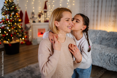 Quadro su tela Daughter kissing mother on cheek during Christmas holiday at home